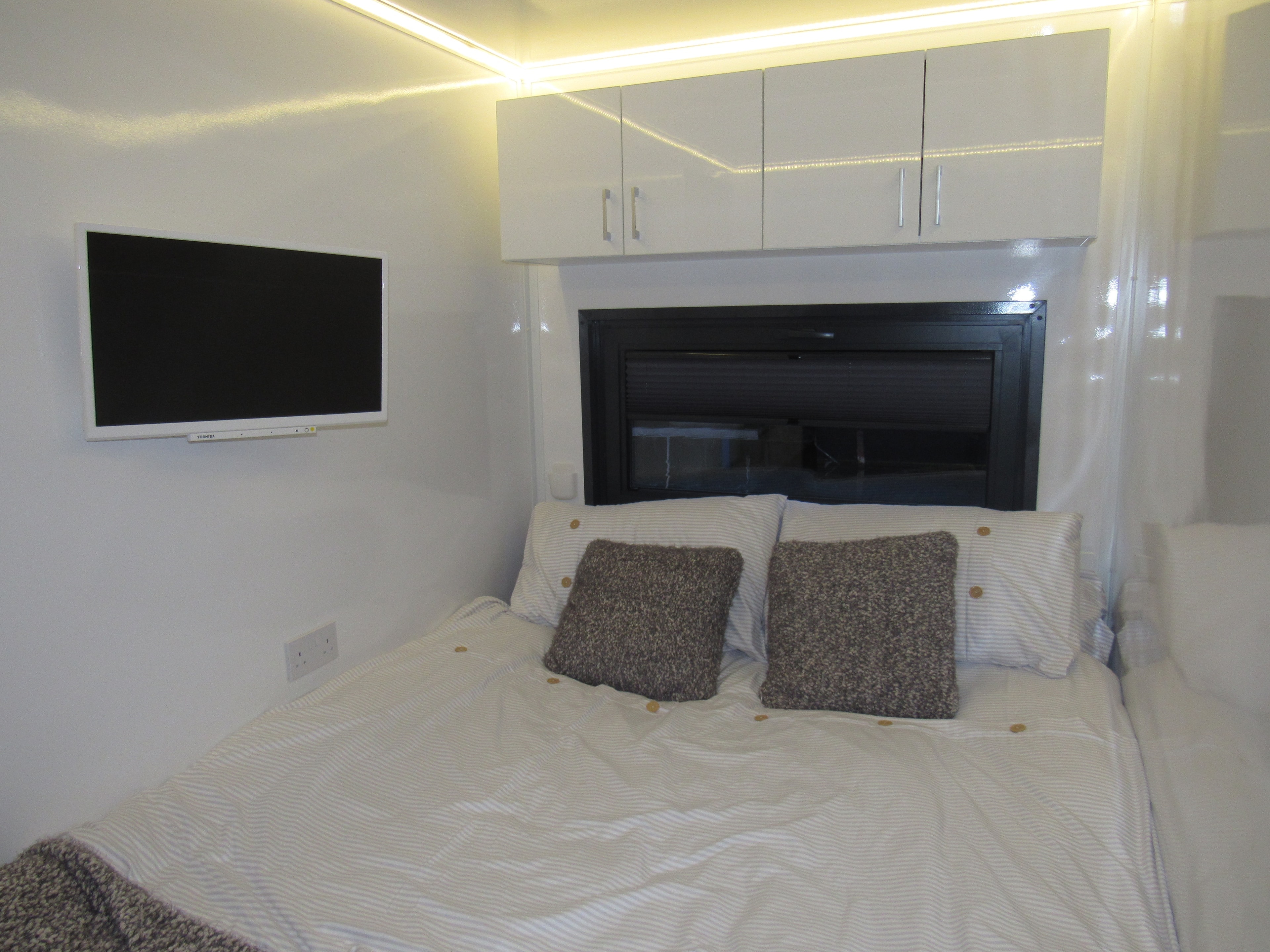 Bedroom with ambient LED lighting, overhead cabinets and king bed
