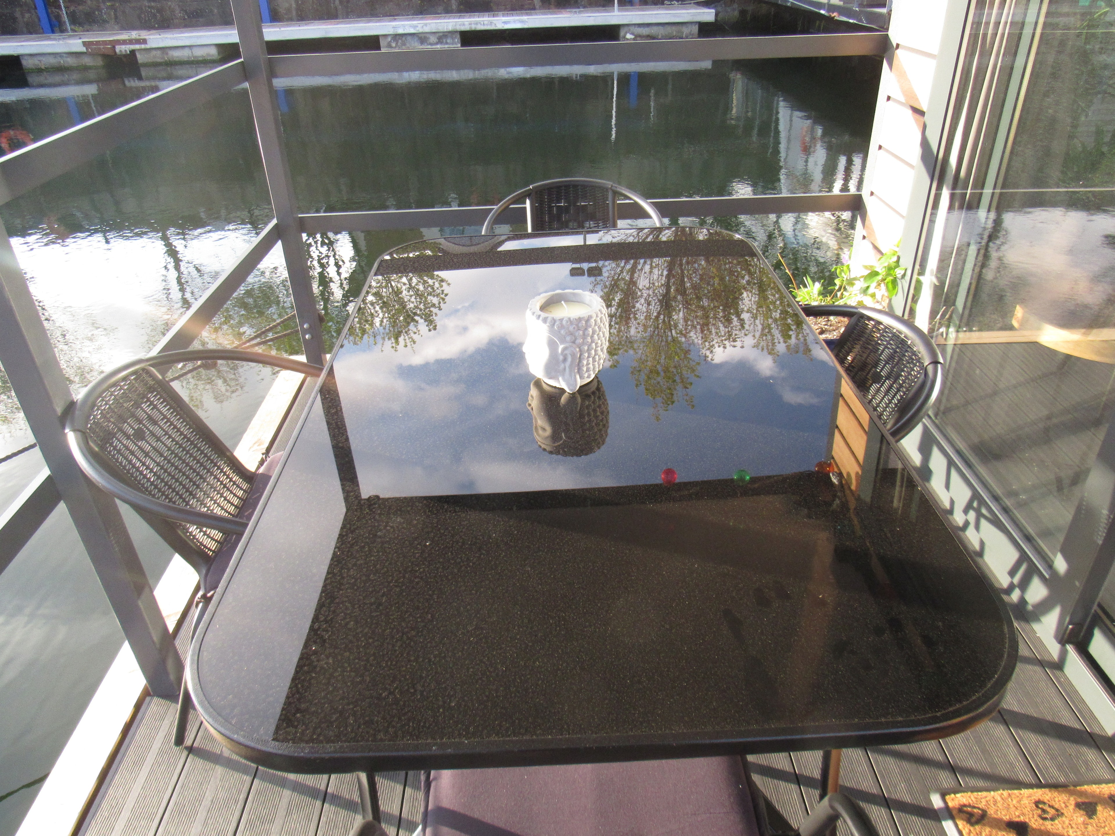 Close-up of the balcony table and chairs with the marina reflected in the glass top